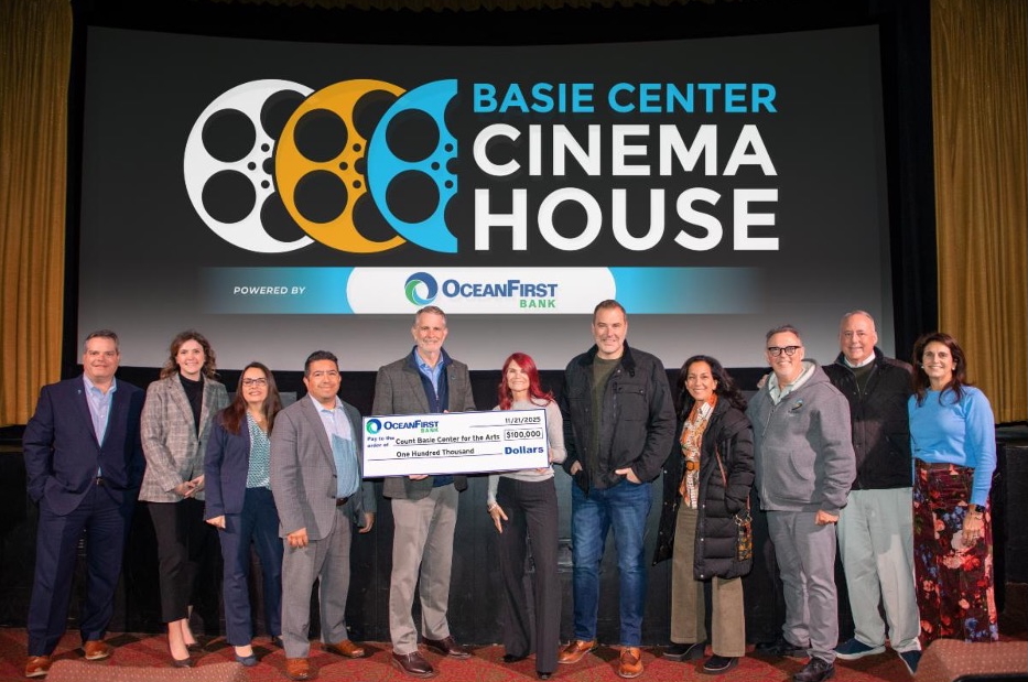 Fotografía de miembros de OceanFirst Bank y del Centro de Artes Count Basie posando frente a una pantalla de cine que anuncia el nuevo nombre del recinto: Basie Center Cinema House. 
